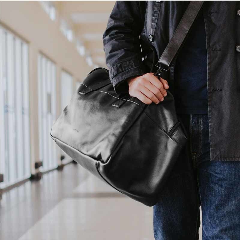 Nordweg black leather weekender duffel hand-carried with shoulder strap in a bright hallway
