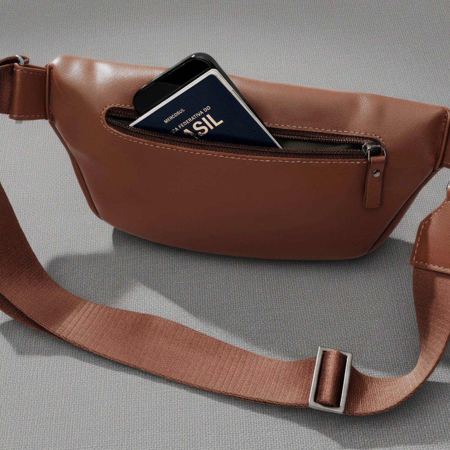 Back pocket of the Nordweg Pulse Leather Sling Bag in caramel open with a passport and smartphone inside