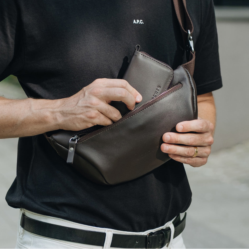 Person holding a Nordweg Traveler Pro NW110 brown leather wallet with a blurred background