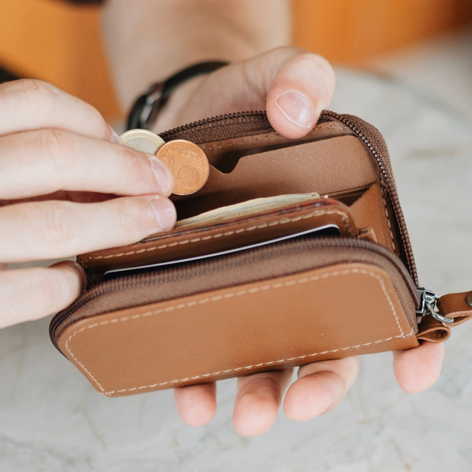 Person holding a brown wallet with coins and cards.