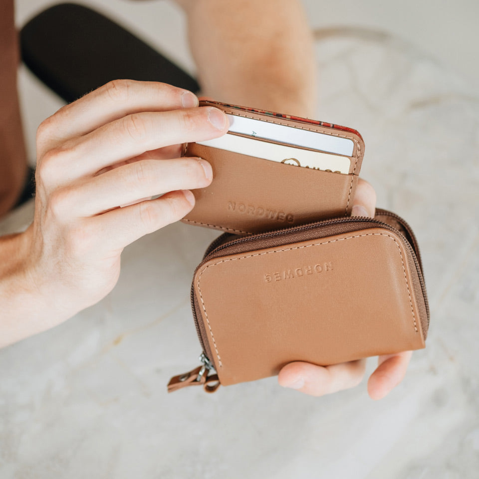 Person holding a brown leather wallet with 'Nordweg' branding.