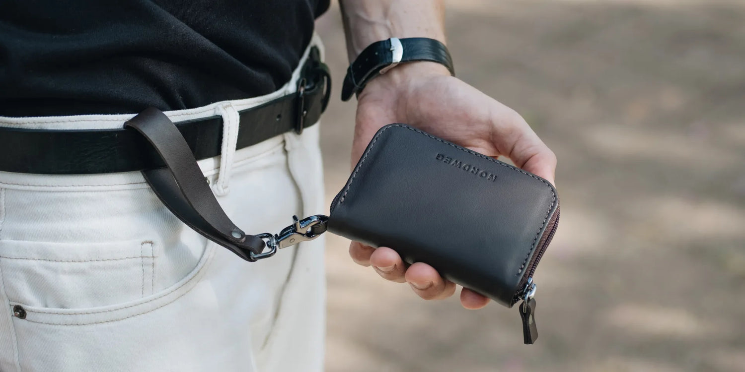 Person holding a black leather wallet with safe loop