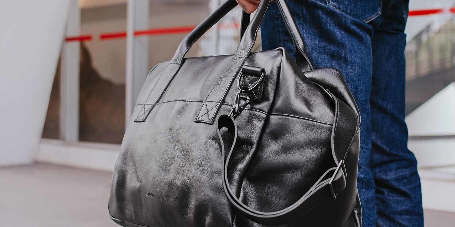 Nordweg black leather weekender duffel side carry with shoulder strap in a travel banner