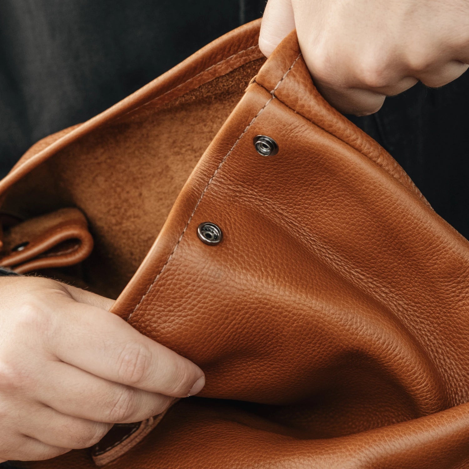 Interior detail showing the snap button closure on the Nordweg Legacy Leather Backpack in cognac leather