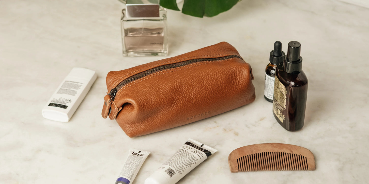 Nordweg Legacy Organizer in cognac leather on a marble surface surrounded by grooming essentials including a comb, serum, and fragrance